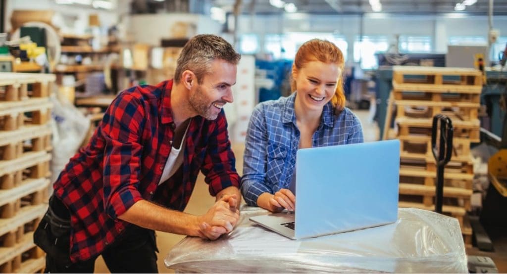 man and woman using laptop computer in small business setting