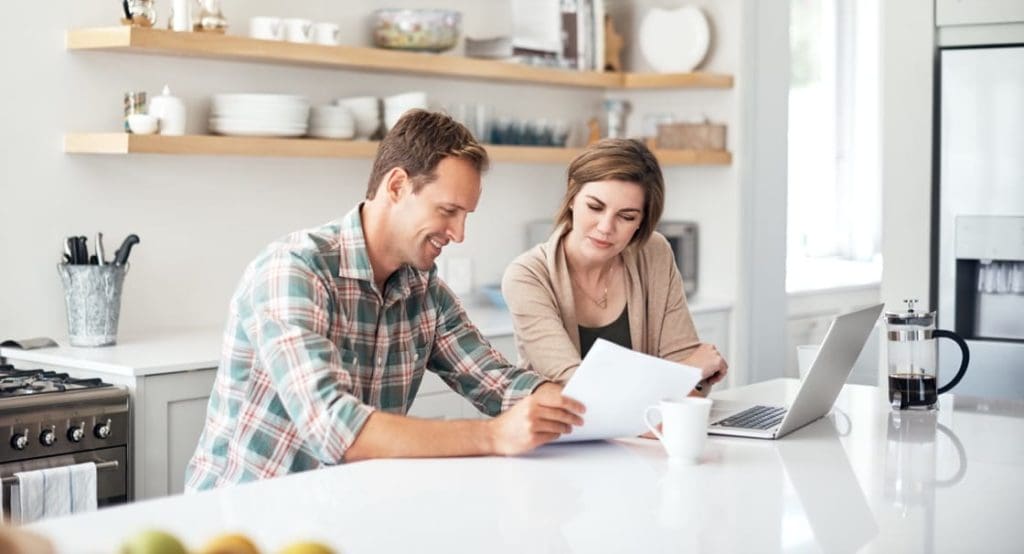 man and woman reviewing documents in home kitchen
