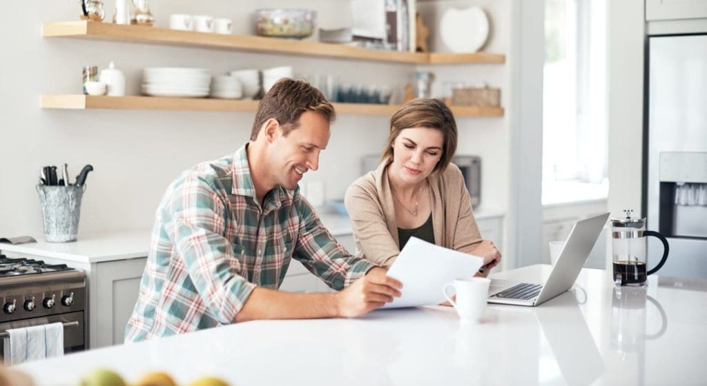 man and woman reviewing documents in home kitchen