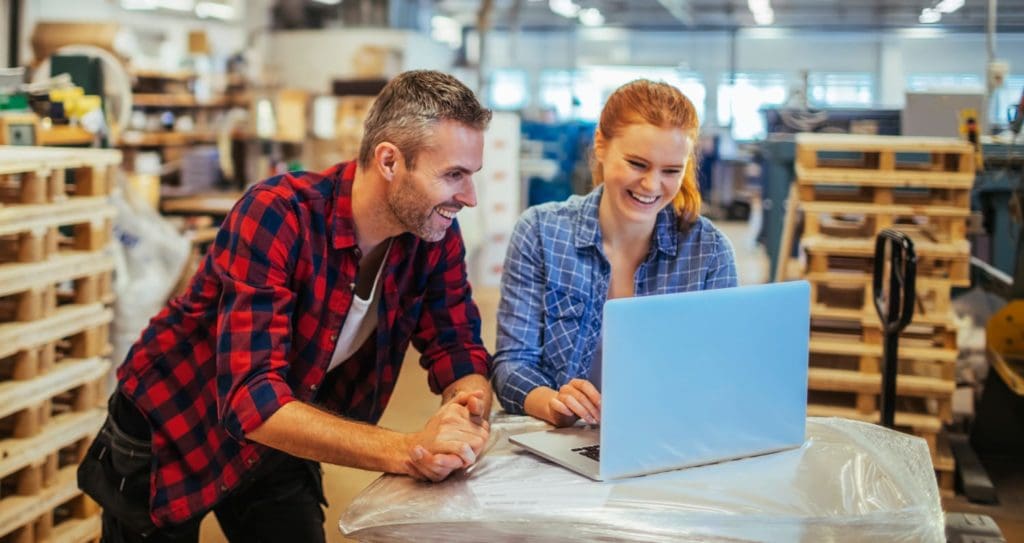 man and woman using laptop computer in small business setting