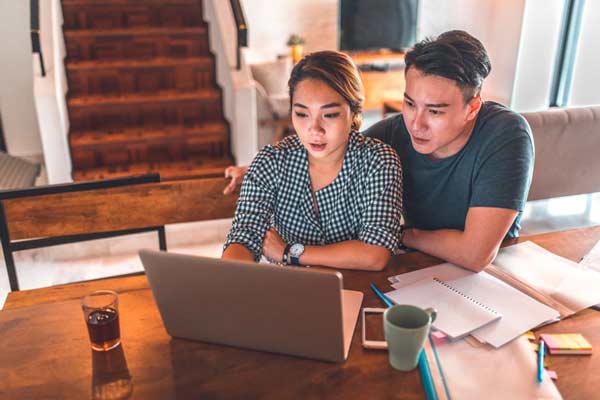 married couple in home at table using computer