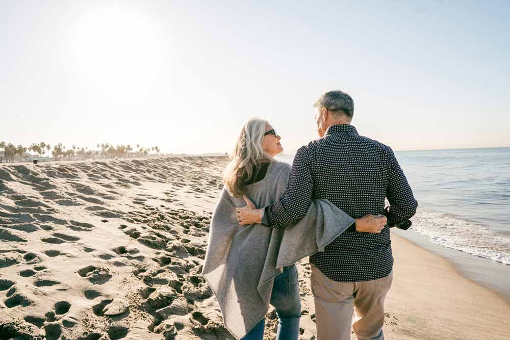 An image of a retired couple walking on a beach.
