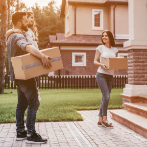 A man and woman carrying boxes to a house.