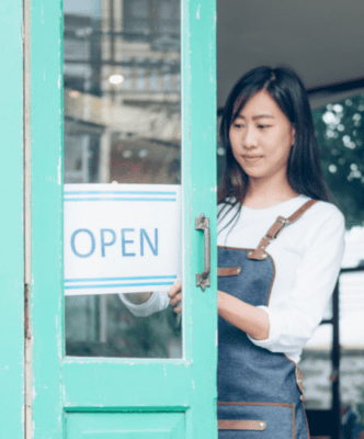 An image of a woman inside a building with an open sign on the door.