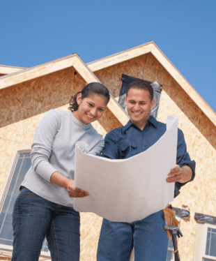 Couple looking at blueprints outside of home construction