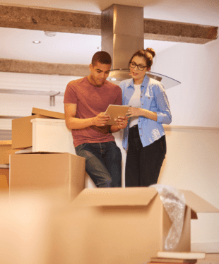 A man and woman standing inside a building with boxes around them.