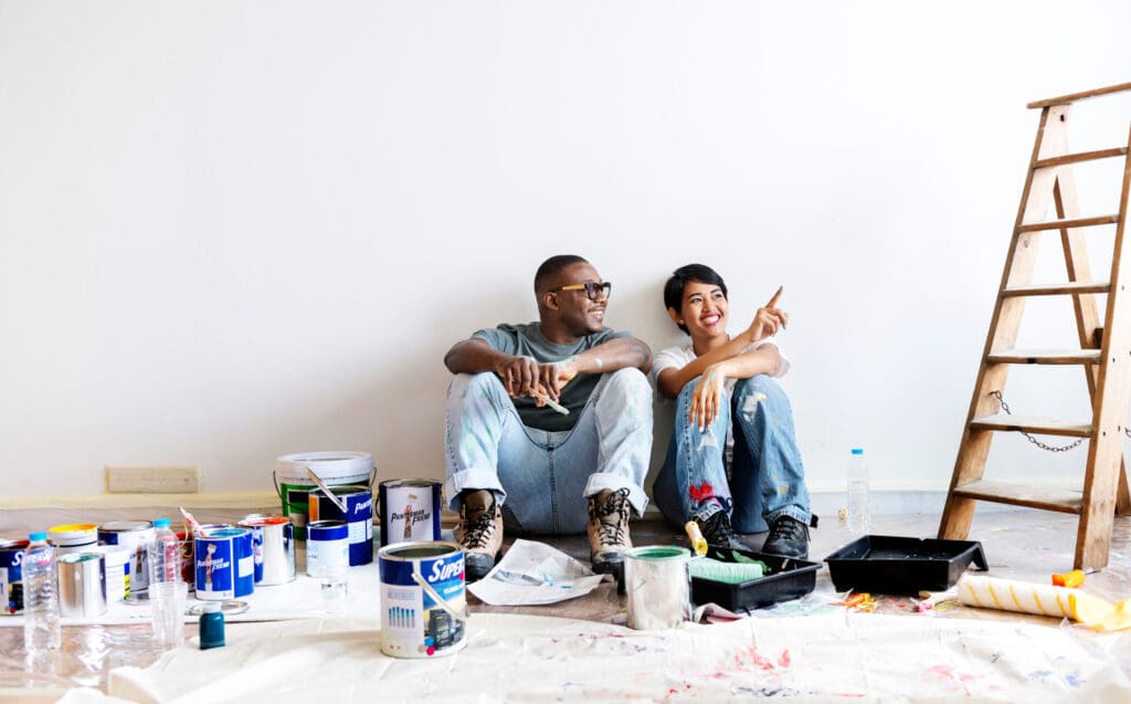 A smiling couple taking a break from painting a room